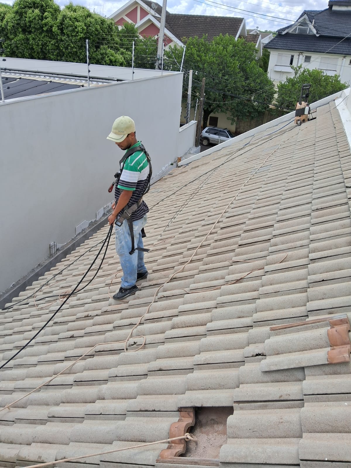 Profissional com cinto de segurança pintando telhado com equipamento airless
