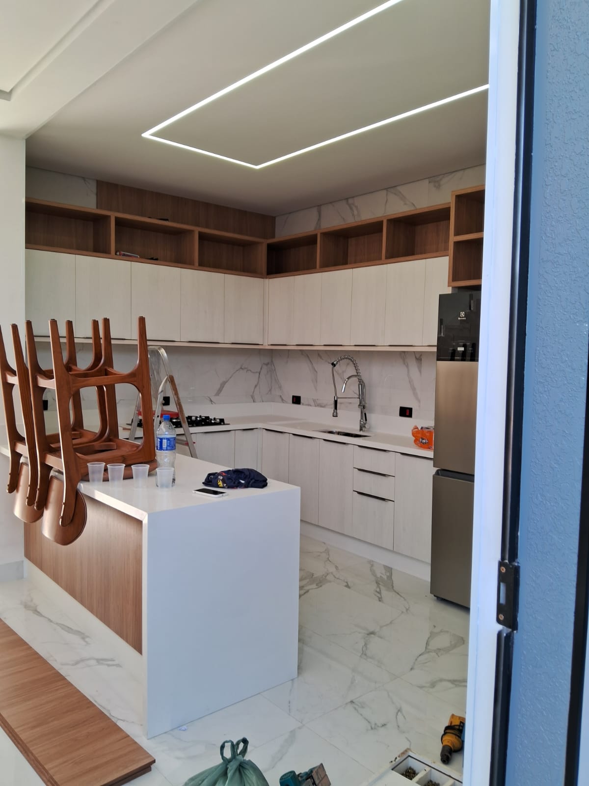 Cozinha gourmet com paredes claras pintadas, marcenaria clara e bancada branca